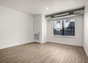 Thumbnail 9 of 28 - A room with a white door, a window with blinds, and a wooden floor.