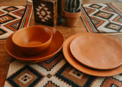 Thumbnail 8 of 12 - a wooden table topped with orange plates and a cactus