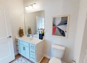 Thumbnail 49 of 49 - A bathroom with a white toilet, sink, and a painting on the wall.