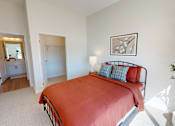 Thumbnail 48 of 49 - A bedroom with a red bed and a plant on the side table.