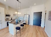 Thumbnail 40 of 49 - A kitchen with a bar and stools in the middle.