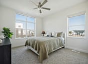 Thumbnail 23 of 49 - A bedroom with a bed, a ceiling fan, and a window overlooking a cityscape.
