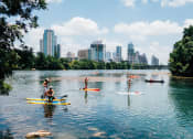 Thumbnail 12 of 12 - a group of people on kayaks on a lake with a city in the background