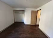 Thumbnail 10 of 18 - A room with a brown floor and white walls.
