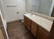 Thumbnail 7 of 18 - A bathroom with a toilet, sink, mirror, and lighting fixture.