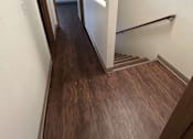 Thumbnail 11 of 18 - A hallway with wood flooring and white walls.