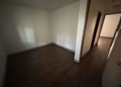 Thumbnail 8 of 18 - A room with wooden floors and white walls.