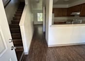 Thumbnail 12 of 18 - A white door is on the left of a hallway with wooden floors and a staircase.