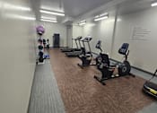 Thumbnail 21 of 27 - A gym with treadmills, elliptical machines, and a rowing machine.