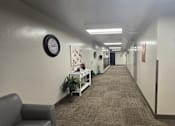 Thumbnail 23 of 27 - A long hallway with a clock on the wall and a wreath on the other wall.