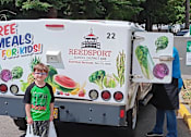 Thumbnail 5 of 5 - A truck with a Reedsport school district logo and a sign that says "Free Meals for Kids!" is parked in a parking lot.