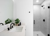 Thumbnail 21 of 24 - A modern bathroom with a white sink and a walk-in shower at Miles at Ybor Apartments, Florida, 33605