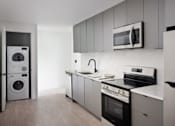 Thumbnail 18 of 24 - A modern kitchen with a washing machine and a microwave at Miles at Ybor Apartments, Tampa 33605