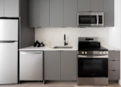 Thumbnail 19 of 24 - A modern kitchen with a white refrigerator, microwave, and stainless steel appliances at Miles at Ybor Apartments, Tampa, FL, 33605
