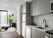 Thumbnail 17 of 24 - A modern kitchen with white cabinets and a black stove top at Miles at Ybor Apartments, Tampa, FL
