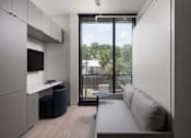 Thumbnail 16 of 24 - A modern living room with a couch, a chair, and a television at Miles at Ybor Apartments, Tampa