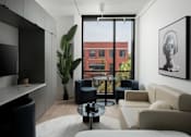 Thumbnail 13 of 24 - A living room with a large window overlooking a red building at Miles at Ybor Apartments, Florida, 33605
