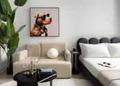Thumbnail 11 of 24 - A living room with a beige couch, a black coffee table, and a framed picture of a dog wearing sunglasses at Miles at Ybor Apartments, Tampa