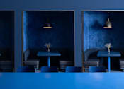 Thumbnail 6 of 24 - A blue table is in the middle of a room with three chairs and three lamps at Miles at Ybor Apartments, Tampa, FL, 33605