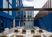 Thumbnail 7 of 24 - A modern outdoor seating area with white furniture and a pool at Miles at Ybor Apartments, Tampa, Florida