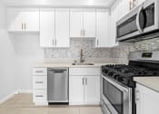 Thumbnail 2 of 18 - a white kitchen with stainless steel appliances and white cabinets at Hollywood Vista in Los Angeles, CA