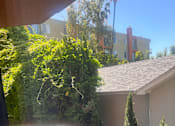 Thumbnail 22 of 24 - A balcony with a metal railing and a view of a building and trees.