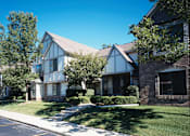 Thumbnail 16 of 33 - River Oaks at Rochester Hills Apartments exterior with townhouse-style buildings, landscaped lawn and walkway.