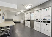Thumbnail 33 of 33 - A clean, well-organized laundry room with a shopping cart and washing machines.