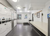Thumbnail 32 of 33 - A long hallway with a series of lockers on the left and a bench on the right.