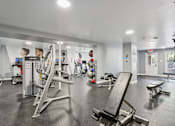 Thumbnail 26 of 33 - A gym with a variety of equipment including weights and cardio machines.