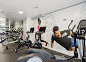Thumbnail 27 of 33 - A man is working out on a chest press machine in a gym.