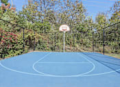 Thumbnail 31 of 33 - A basketball court surrounded by a fence and trees.