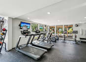 Thumbnail 27 of 33 - River Oaks at Rochester Hills Apartments fitness center with treadmills, ellipticals, spin bikes, and large windows.