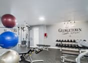 Thumbnail 21 of 33 - Georgetown Apartments of St. Louis fitness center with weight rack, benches, and stability balls.
