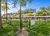 Thumbnail 17 of 33 - River Oaks at Rochester Hills fenced dog park with grassy play area and townhomes in the background.