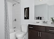 Thumbnail 6 of 33 - Apartment bathroom at River Oaks at Rochester Hills with tub/shower, toilet, and dark wood vanity.