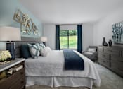 Thumbnail 4 of 33 - Spacious bedroom at River Oaks at Rochester Hills Apartments with king bed, accent wall, dresser and window seat.