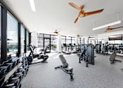 Thumbnail 11 of 24 - A gym with a variety of equipment including treadmills, weights, and exercise machines.
