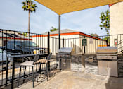 Thumbnail 6 of 33 - A patio with a grill and chairs under a canopy.