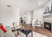 Thumbnail 9 of 45 - A living room with a grey couch, a black coffee table, a fireplace, and a painting on the wall.