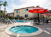 Thumbnail 32 of 33 - A pool with a slide and a table with chairs and umbrellas.