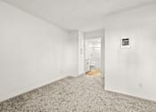 Thumbnail 14 of 36 - A room with a carpeted floor and a doorway leading to another room.