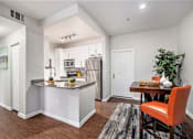 Thumbnail 1 of 45 - A kitchen with a bar area and a dining table with chairs.