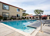 Thumbnail 30 of 33 - A swimming pool in front of a building with a red roof.
