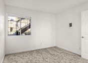 Thumbnail 17 of 36 - A room with a white door, a window, and a carpeted floor.