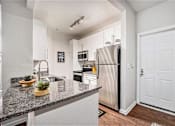 Thumbnail 3 of 45 - A kitchen with a granite countertop and stainless steel appliances.