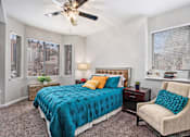 Thumbnail 5 of 45 - A bedroom with a bed, chair, and ceiling fan.