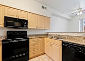 Thumbnail 7 of 19 - A kitchen with black appliances and wooden cabinets.