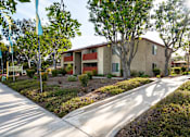 Thumbnail 5 of 33 - A sunny day at a residential area with apartment buildings and a sidewalk.
