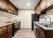 Thumbnail 19 of 36 - A kitchen with brown cabinets and black appliances.
